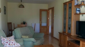 A living room with a sofa, a coffee table, a television, and wooden cabinets. - Family-Friendly Apartment with Pool, Balcony, and Parking in Jaca (Jaca)