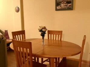 Cozy dining area with a round table and four chairs, featuring a vase with flowers and a framed picture.