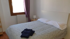 A neatly made bed with a patterned bedspread, a white pillow, and a folded dark blue towel on the bed. - Spacious 2-bedroom apartment with parking in Villanúa (Villanúa)
