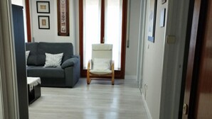 A living room with a grey sofa, a white armchair, and a wooden floor. - Central Apartment for 4 with Parking in Jaca's Main Street (Jaca)