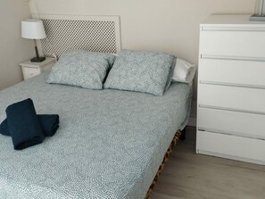 A bed with a patterned bedspread, two pillows, and a folded dark blue blanket. - Central Apartment for 4 with Parking in Jaca's Main Street (Jaca)