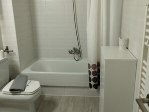 A bathroom with a bathtub, toilet, and a small cabinet. - Central Apartment for 4 with Parking in Jaca's Main Street (Jaca)