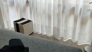 A room with a bed, a small white ottoman, and sheer white curtains. - Central Apartment for 4 with Parking in Jaca's Main Street (Jaca)