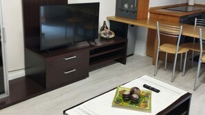 A compact kitchen with a dark wooden cabinet, a built-in TV, and a dining area with a table and chairs. - Central Apartment for 4 with Parking in Jaca's Main Street (Jaca)