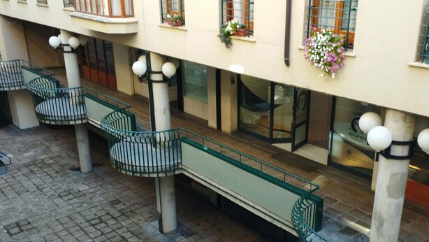 A courtyard with a glass balustrade, a bench, and a building with flower boxes. - Central Apartment for 4 with Parking in Jaca's Main Street (Jaca)