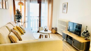 Ein Wohnzimmer mit einer Couch, einem Couchtisch, einem Fernseher und einer kleinen Weihnachtstanne.