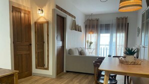 Ein Essbereich mit einem Holztisch und Stühlen, einer Couch und einem Fenster mit Vorhängen.
