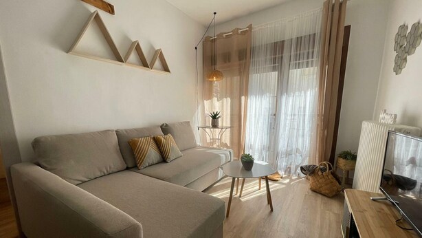 Ein modernes Wohnzimmer mit einer Couch, einem kleinen runden Tisch und einem Fernseher.
