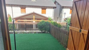Een terras met kunstgras, een houten omheining en een betegelde vloer.