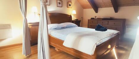 Un dormitorio con cama de madera, mesita de noche, cómoda y ventana con cortinas.