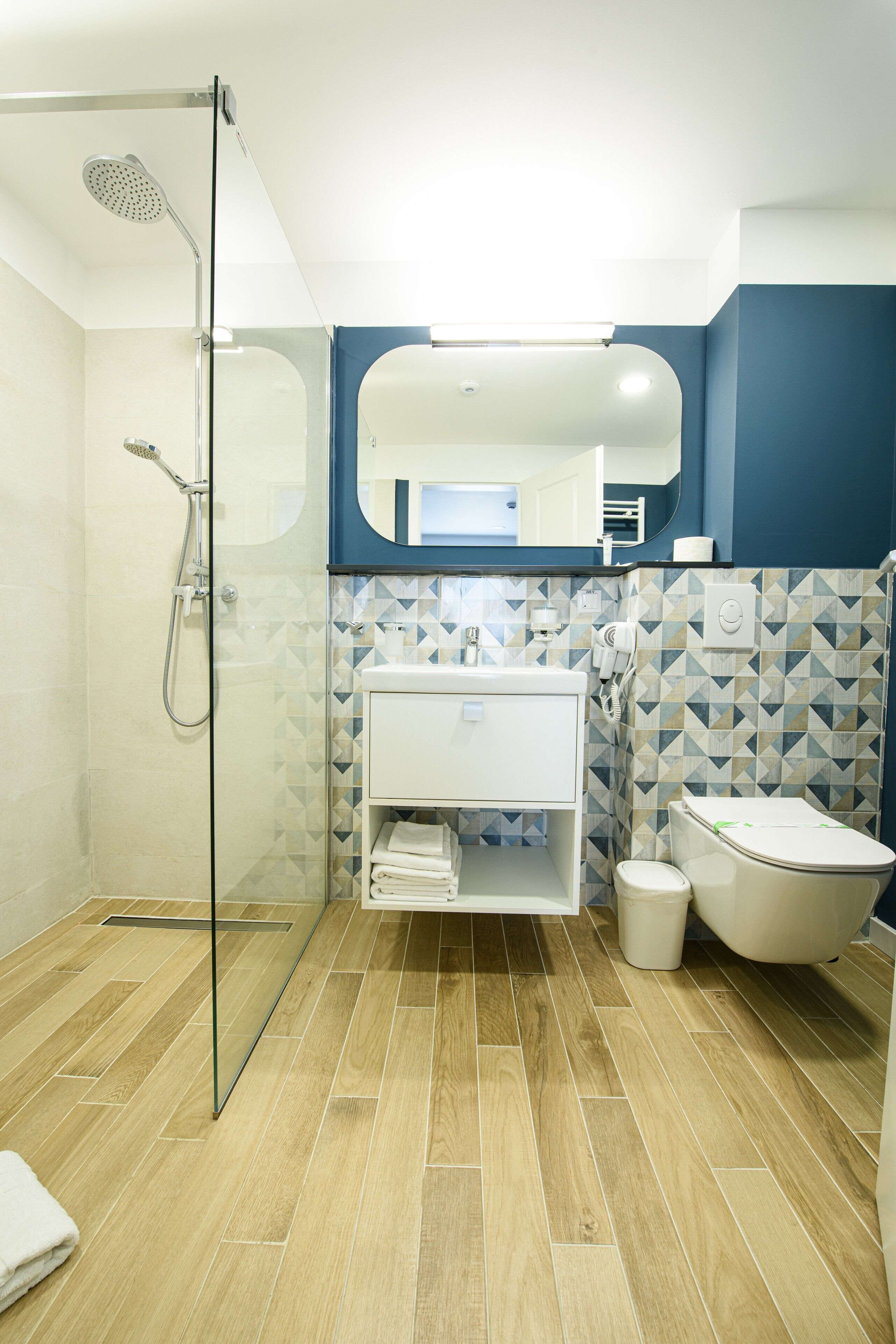 A modern bathroom with a glass shower enclosure, a white sink, and a toilet.