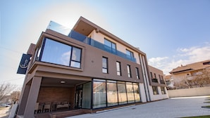 A modern two-story building with large windows, a covered outdoor seating area, and a flat roof. - Vila Sarisa (Deva)