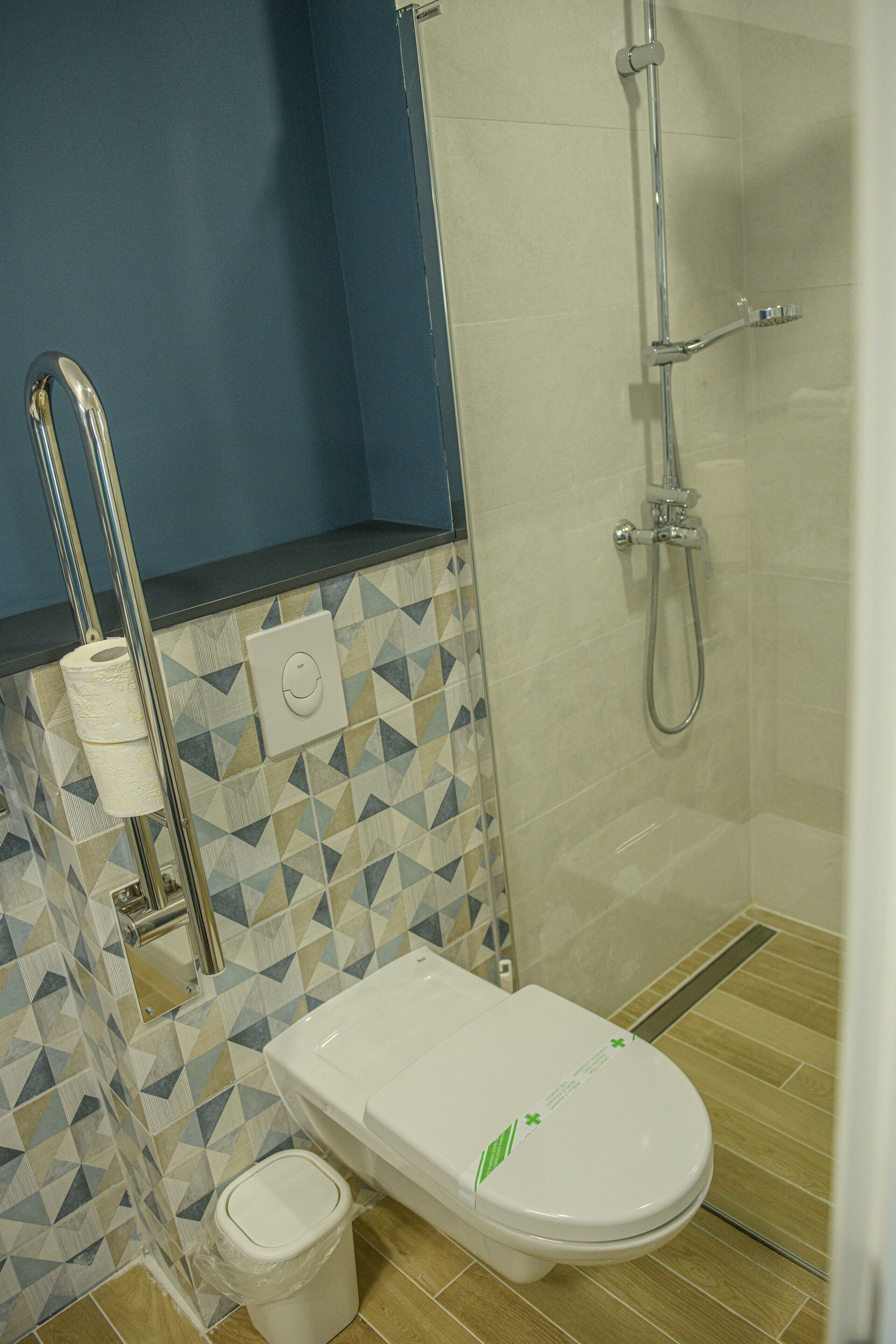 A bathroom with a toilet, a shower, and a toilet paper holder.