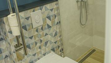 A bathroom with a toilet, a shower, and a toilet paper holder.