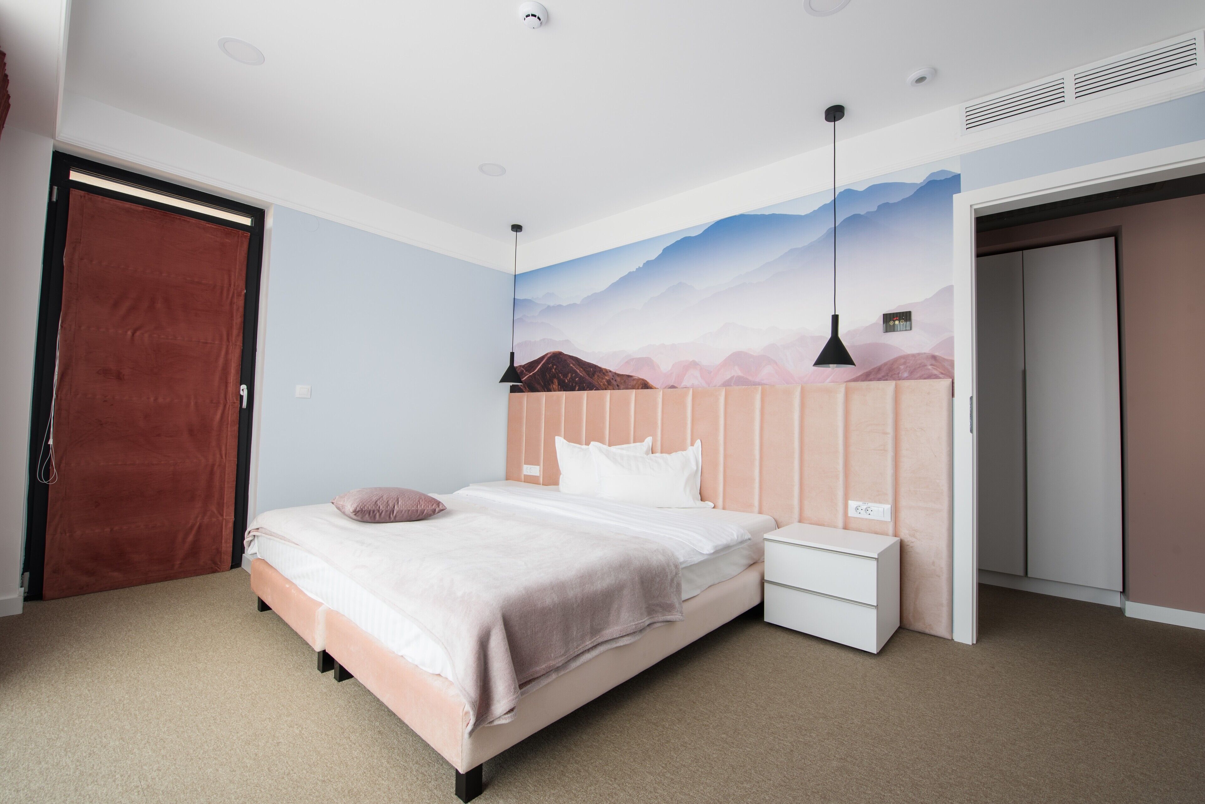 Un dormitorio con cama, mesita de noche y un mural en la pared.