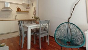 Un coin repas avec une table et des chaises blanches, un luminaire suspendu et une décoration faite de branches.