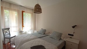 Une chambre avec deux lits, une chaise, une table de chevet et un luminaire suspendu.