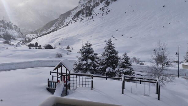 Schneebedeckte Landschaft mit einem Spielplatz und einem Berg im Hintergrund.