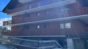 Un edifici de diverses plantes amb balcons, una base de pedra i un senyal que indica que és un hotel.