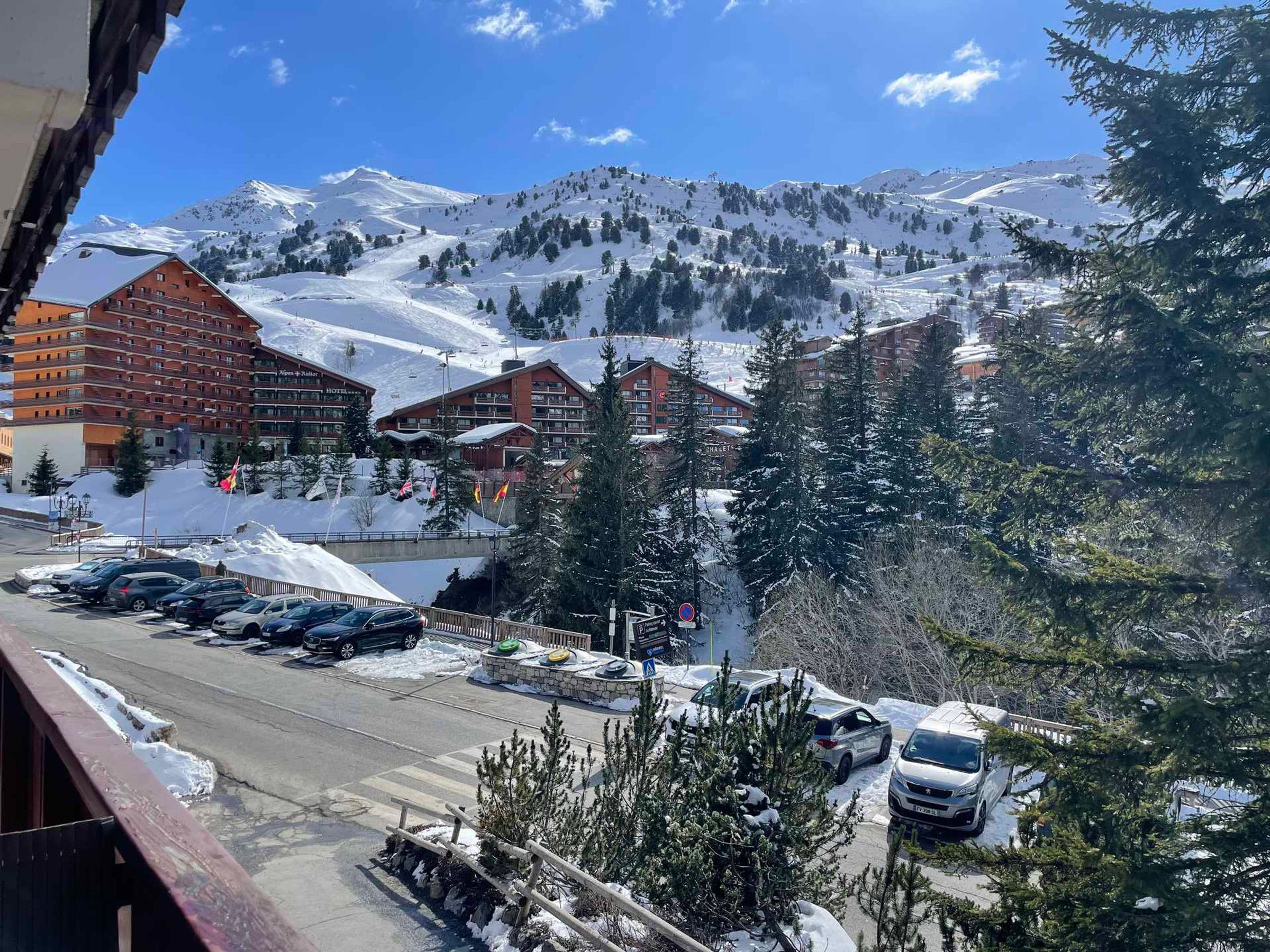 A hotel with multiple buildings, a parking lot with cars, and a snowy mountain backdrop.