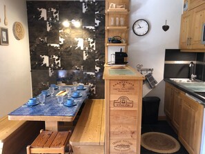 A compact kitchen with a wooden table set for dining, a coffee machine, and a clock on the wall. - Cosy apartment for 4 in Méribel Mottaret (Méribel)
