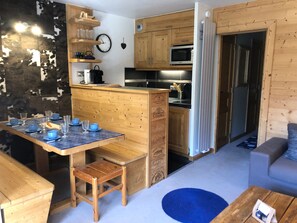A compact kitchen with wooden cabinets, a microwave, and a refrigerator.
