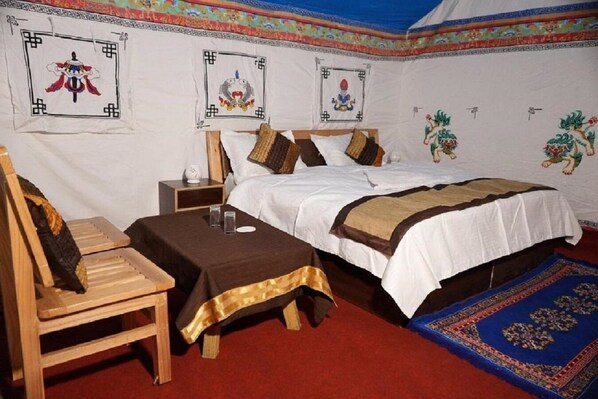 A traditional room with a bed, wooden chair, and a small table.