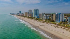 A coastal cityscape with high-rise buildings along a sandy beach. - Meridian Plaza Unit 1402 - Oceanfront! (Myrtle Beach)