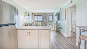 A spacious kitchen with a central island, wooden cabinets, and a view to the dining area.
