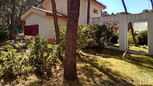 Una casa con facciata bianca e persiane rosse, circondata da alberi e un prato.