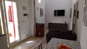 Un soggiorno con divano, televisore a parete e zona pranzo con tavolo e sedie.