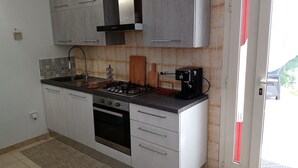 Una cucina compatta con piano cottura a gas, forno e arredamento moderno.