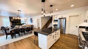 A modern kitchen with a central island, stainless steel appliances, and a dining area with a large table and chairs.