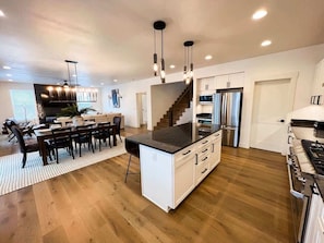 A modern kitchen with a central island, stainless steel appliances, and a dining area with a large table and chairs.