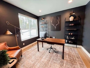 Un bureau moderne avec un bureau en bois, un canapé en cuir et une grande fenêtre.