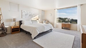 Una camera da letto con un letto, comodini, un appendiabiti, una cassettiera, una finestra con vista e un elemento decorativo a parete.