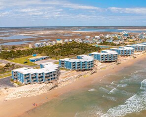 A beachfront hotel with multiple blue buildings, a sandy beach, and a view of the ocean.