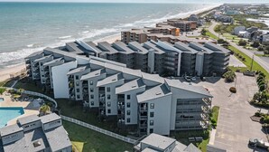A modern apartment complex with multiple buildings, a swimming pool, and a view of the beach and ocean. - 1310 Shipwatch Villas - 3BR Oceanfront Condo in North Topsail Beach with Community Pool & Elevato... (North Topsail Beach)