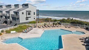 A pool area with two separate pools, a lounge area with sun loungers, and a view of the ocean. - 1310 Shipwatch Villas - 3BR Oceanfront Condo in North Topsail Beach with Community Pool & Elevato... (North Topsail Beach)