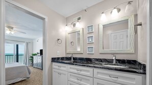 A modern bathroom with a double vanity, marble countertops, and large mirrors. - 1310 Shipwatch Villas - 3BR Oceanfront Condo in North Topsail Beach with Community Pool & Elevato... (North Topsail Beach)