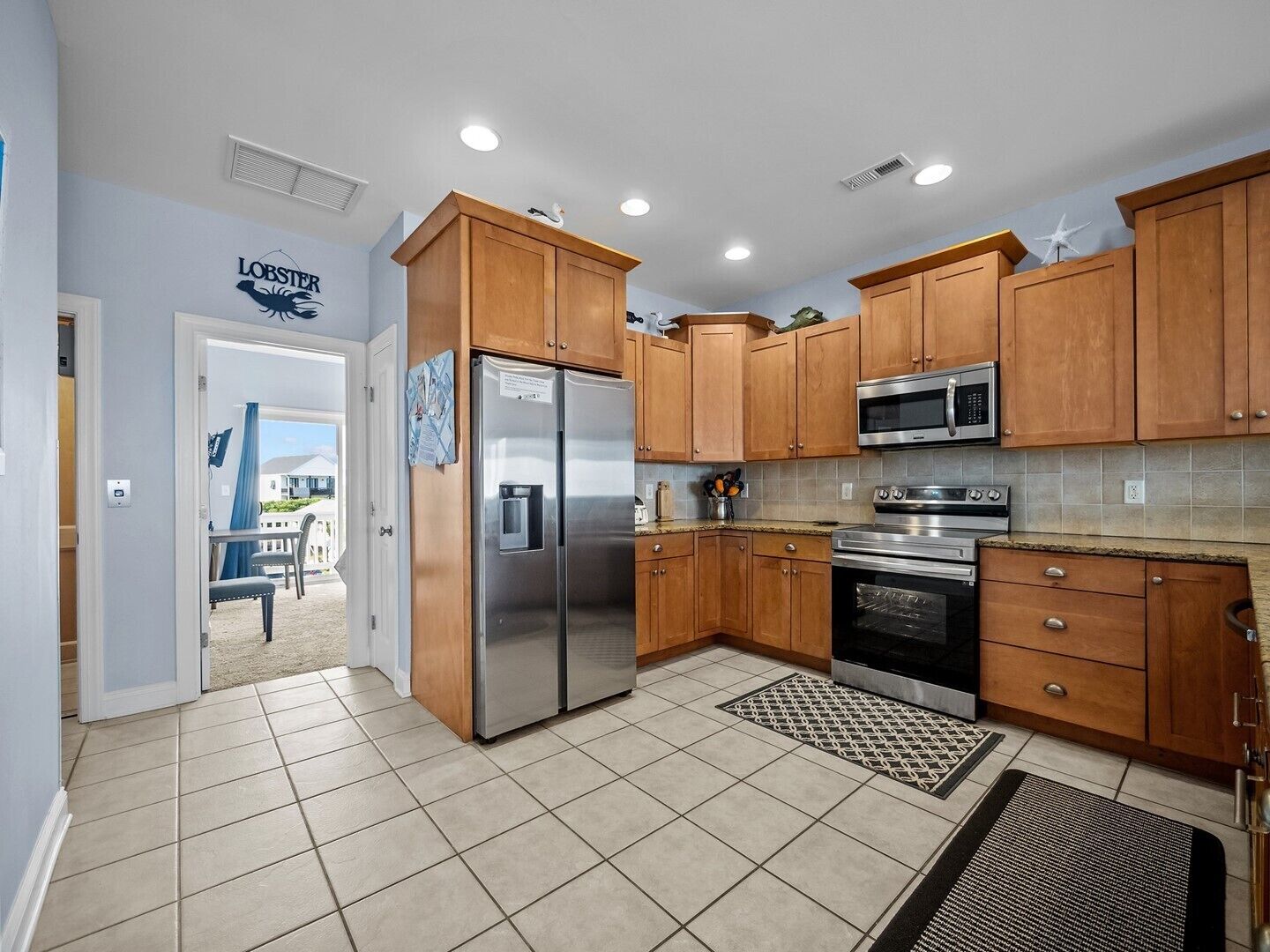 A modern kitchen with wooden cabinets, stainless steel appliances, and a tiled floor.