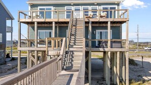 Eine mehrstöckige Holzkonstruktion mit Treppe, Deck und Sitzbereich im Freien.