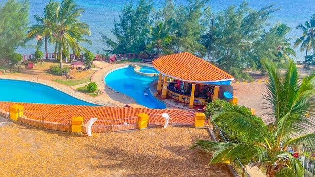 Et resort med en stor swimmingpool, et barområde og udsigt over havet.