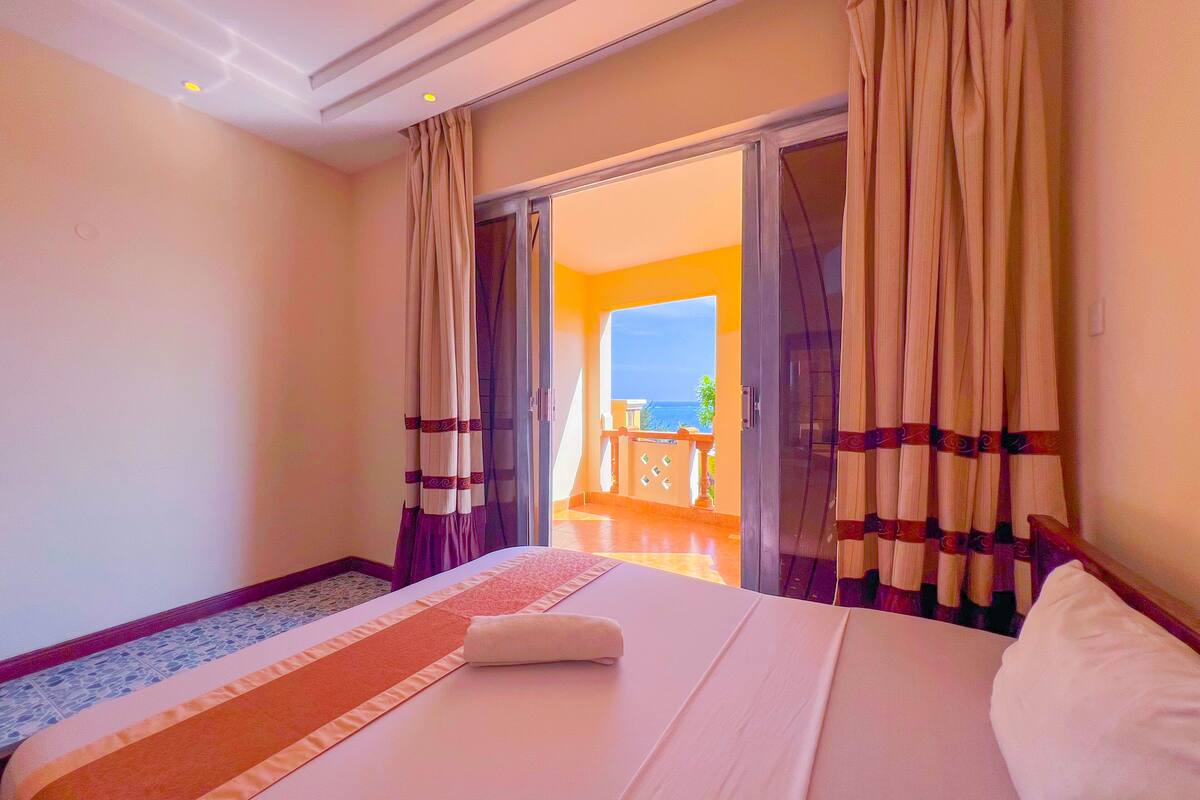 Habitación de hotel con cama, vista al balcón y puerta que da al exterior.