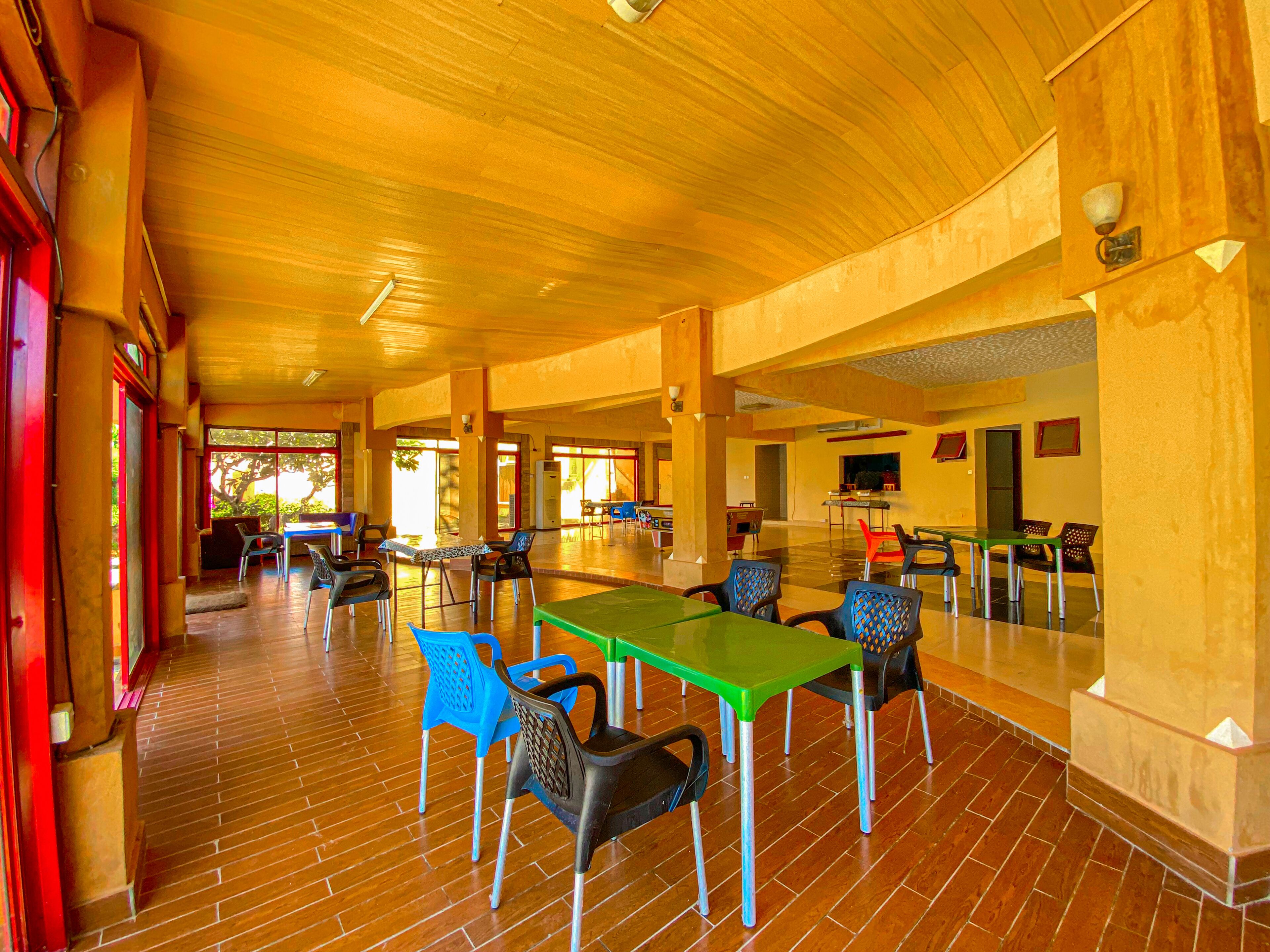 A spacious indoor area with wooden flooring and multiple tables and chairs.