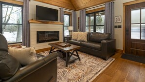Una sala de estar acogedora con chimenea, sofás de cuero y un televisor grande.