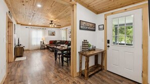 Uma sala de estar ampla com teto de madeira, uma mesa de jantar e um sofá.