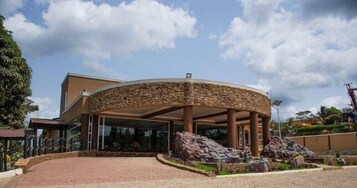 A building with a circular stone facade, a covered entrance, and a paved driveway.