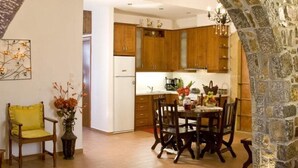 A kitchen with wooden cabinets, a dining table with chairs, and a stone archway. - CRETA GUEST HOUSE ARXONTIKO  15 min to golf club  and 15 minutes to the beach ! (Smari)