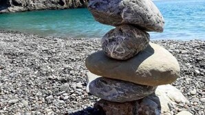 A stack of smooth, rounded stones on a pebbly beach with a rocky cliff in the background. - CRETA GUEST HOUSE ARXONTIKO  15 min to golf club  and 15 minutes to the beach ! (Smari)